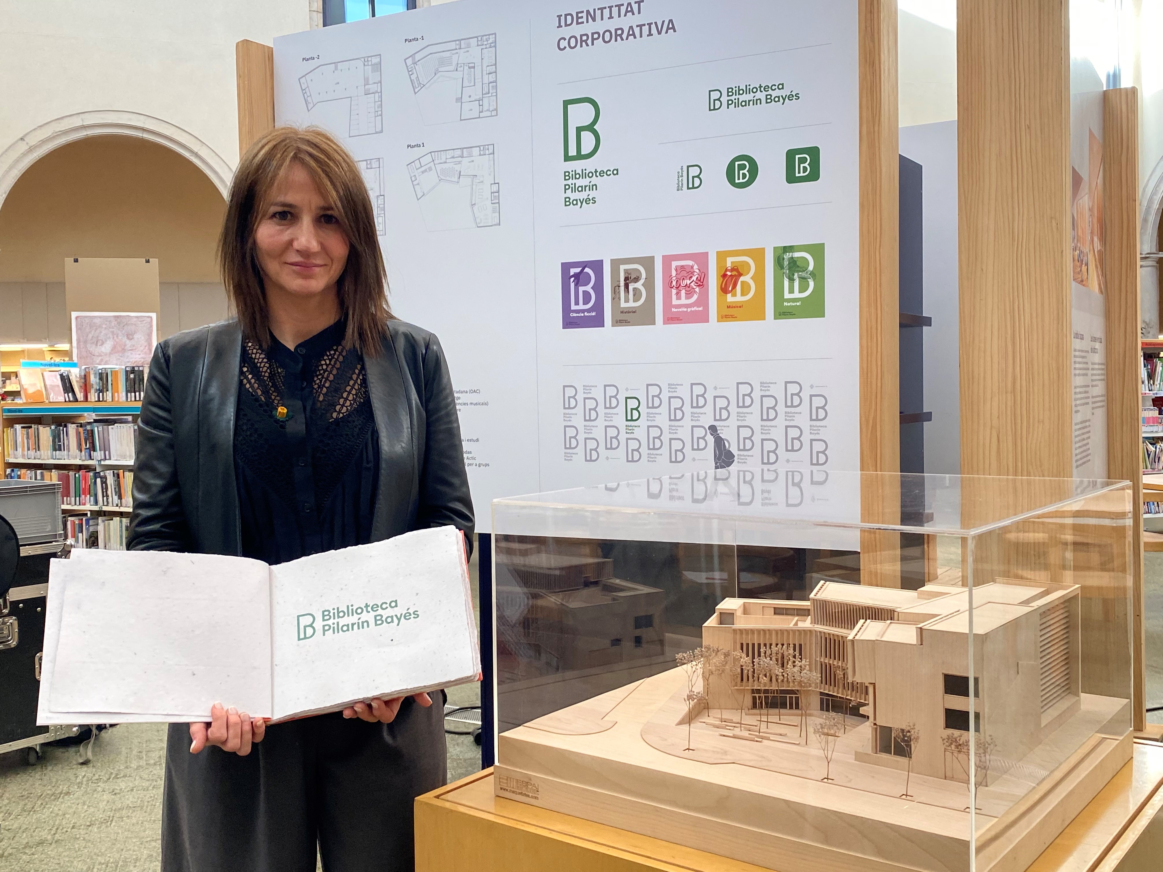 Bet Piella mostra la imatge corporativa de la Biblioteca al costat de la maqueta