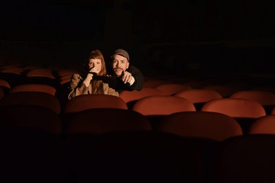 Un noi i una noia asseguts al pati de butaques d'un teatre.