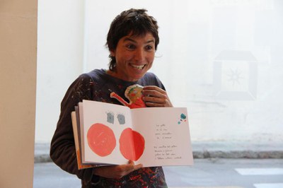 Laia Bedós amb un llibre obert a les mans. En acció davant d'un públic fora de camp..