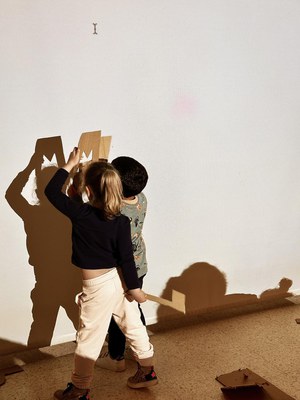Infants jugant amb les seves ombres projectades a la paret..